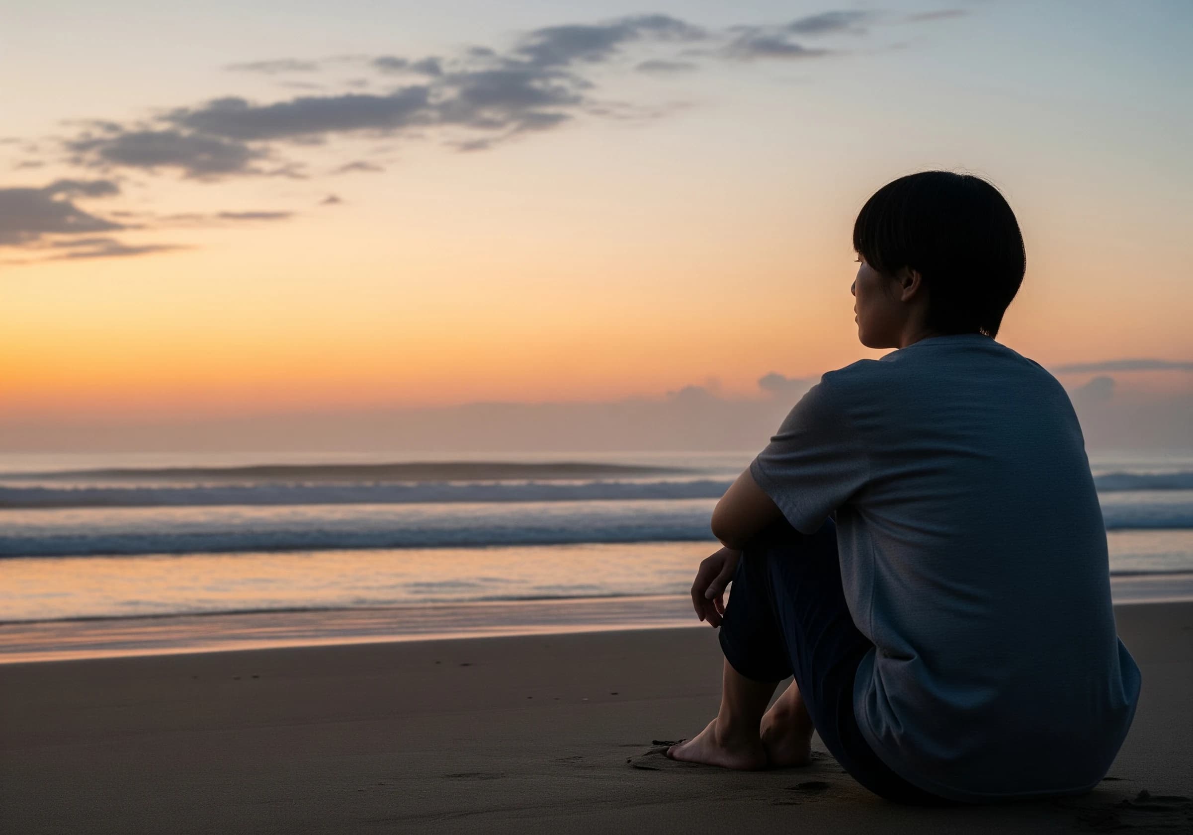 夕暮れの海を見つめる人